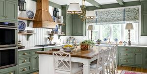 kuhinja s pomirjujočimi zeleno pobarvanimi omaricami, špirovci in oblogami v kombinaciji z belimi stenami, stropom in otokom