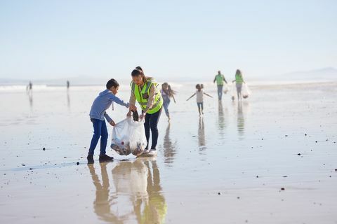 Mati in sin prostovoljno čistita leglo na sončni, mokri peščeni plaži