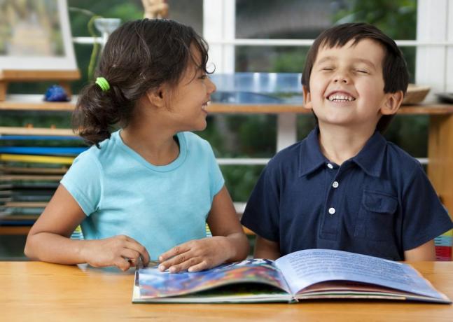 dva smejoča otroka, ki uživata v knjigi v šoli