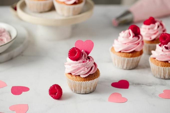 sveže narejeni kolački z malinami na kuhinjskem pultu okusni rožnati kolački z malinovim in papirnatim prelivom v obliki srca