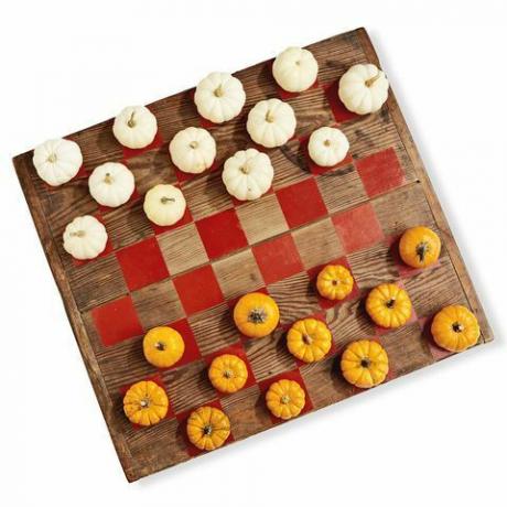 lesena deska, poslikana kot igra v šahovnicah z uporabo mini buč v beli in oranžni barvi