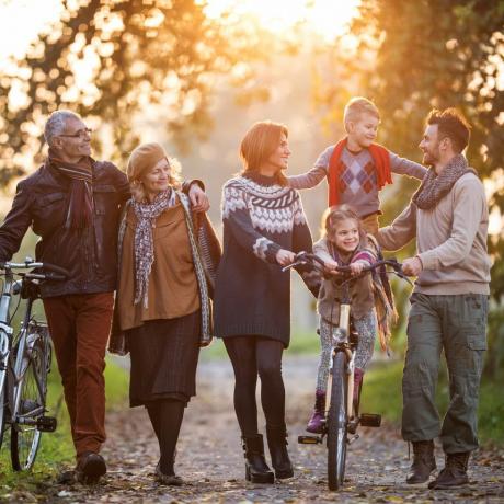 nasmejana večgeneracijska družina, ki se s kolesi sprehaja po naravi in ​​uživa v skupnem času