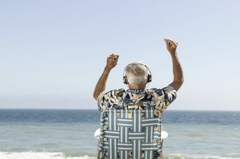 Veseli starec, ki posluša glasbo s pogledom na morje