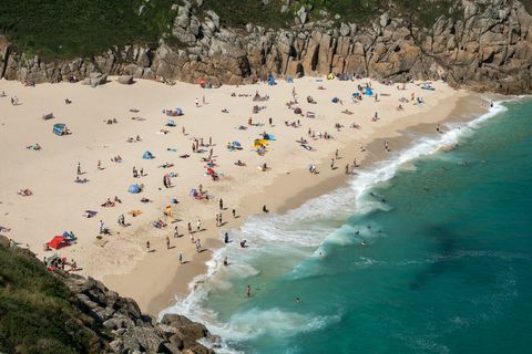 Obiskovalci 28. junija 2018 na plaži Porthcurno v bližini Penzancea namočijo sonce.