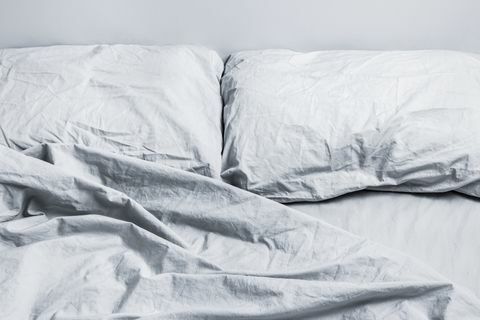 neurejena siva postelja z dvema blazinama pri dnevni svetlobi