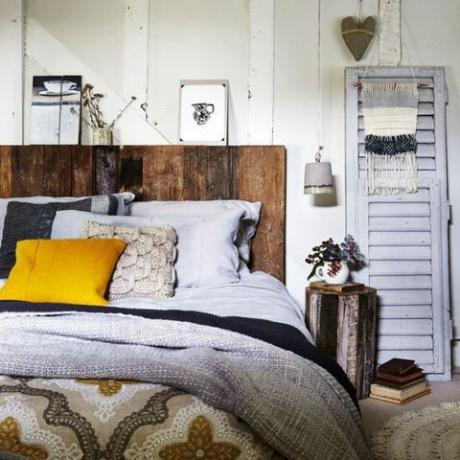 Rustikalna spalnica z lesenim vzglavjem in pletenimi metli