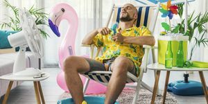 moški preživlja poletne počitnice doma, se hladi z električnimi ventilatorji in sedi na ležalniku