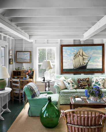 zbrano maine dnevno sobo z zelenim kavčem in velikansko vintage sliko ladje na steni