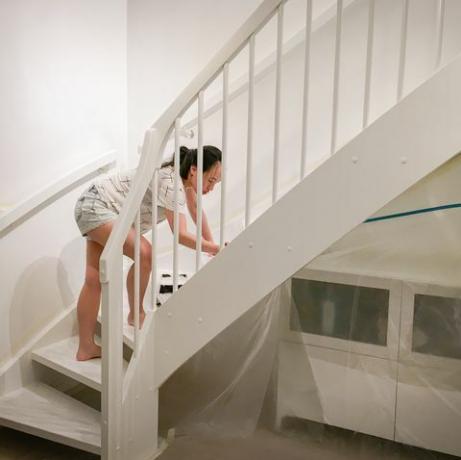 ženska, ki na stopnice nanese svežo belo barvo